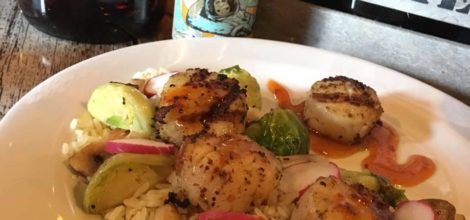 A plate with scallops, brussel sprouts and beer on it.